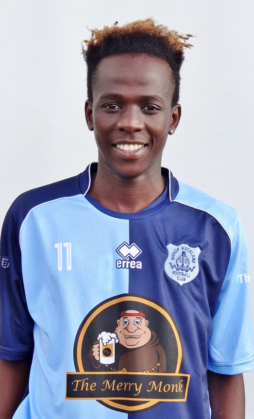 Female football player in Bishop Auckland FC kit bearing sponsor logo, smiling, on a plain background.