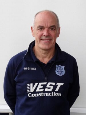 Senior man wearing Bishop Auckland FC sports jacket, smiling, standing against a plain background.