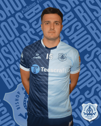 John Doe, Bishop Auckland FC player wearing club kit, standing against team logo background, showcasing football player profile and team pride in Northern England.