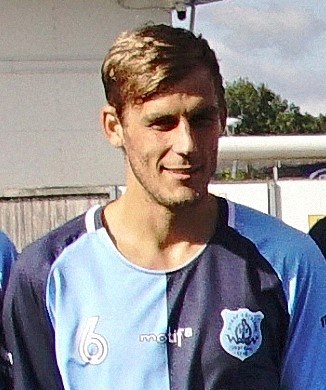 Youth player in Bishop Auckland FC football kit smiling outdoors, representing the club's youth team.