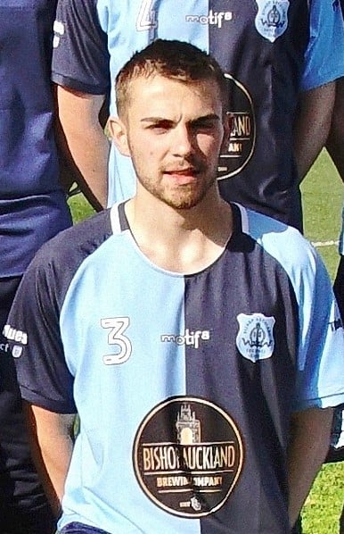 Young football player in Bishop Auckland FC team uniform on the field.