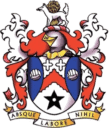 Shield of Bishop Auckland FC with red, white, and blue elements, featuring a lion, stars, and a motto, representing historic football club and local sports heritage.