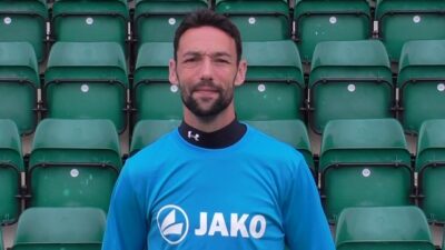 Professional Bishop Auckland FC player in team kit at the stadium.