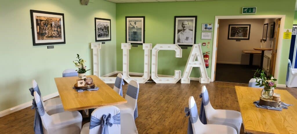 Bright indoor lounge at Bishop Auckland FC with framed historic team photographs and decorative lighting, perfect for hosting supporters and events in a welcoming football club environment.
