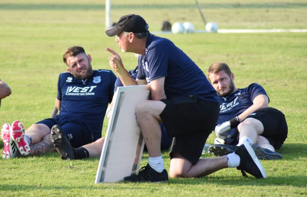 Benching coaching during football training or game strategy discussion at Bishop Auckland FC, a professional football club in England playing in the Northern League, showcasing team leadership and tactical planning.
