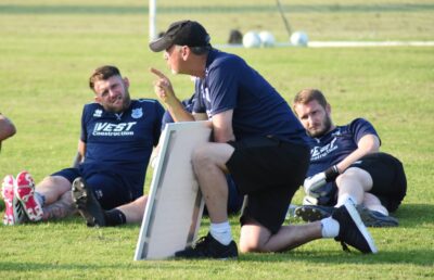 Benching coaching during football training or game strategy discussion at Bishop Auckland FC, a professional football club in England playing in the Northern League, showcasing team leadership and tactical planning.