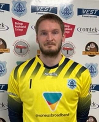 A football player from Bishop Auckland FC in team kit, standing in front of a branded backdrop, showcasing the team’s player roster and organisation.