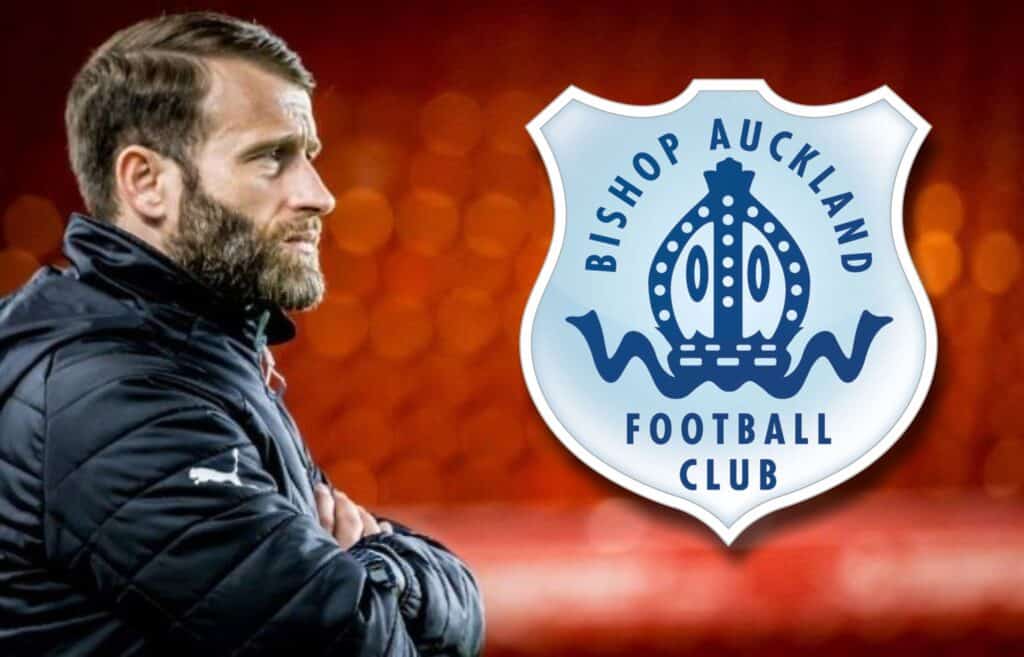 Experienced football coach watching Bishop Auckland FC match with club logo in background.