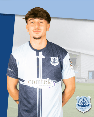 Young male football player in Bishop Auckland FC kit standing outdoors, smiling, representing the club's dedicated sports team and community spirit.