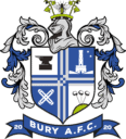 Traditional English football crest featuring Bury AFC, with a shield showing a tower, crossed footballs, and date 2020. Imagery includes a knight's helmet, floral motifs, and a banner with the club's name.
