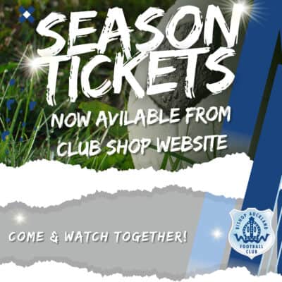 Bright green pitch with a white football in the foreground, promoting Bishop Auckland FC season tickets and matchday experiences for local football supporters.