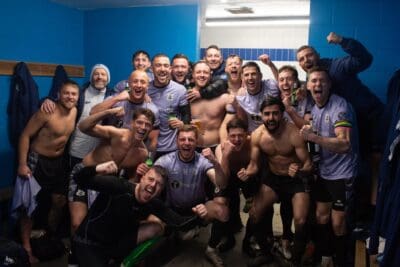 Celebrating Bishop Auckland FC players in the locker room after a victorious match, showcasing team spirit, victory, and football passion.