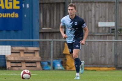 Athletic football player running on the pitch during a match at Bishop Auckland FC.
